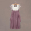 Two-tone dress with white top and mauve skirt on a hanger against a brown background