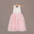 Pink and white dress on a hanger against a brown background