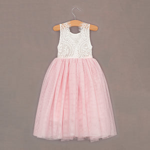 Pink and white dress on a hanger against a brown background
