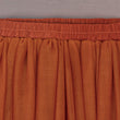 Close-up of a rust-colored fabric skirt with an elastic waistband.