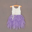 White top and purple tutu skirt dress on a hanger against a brown background