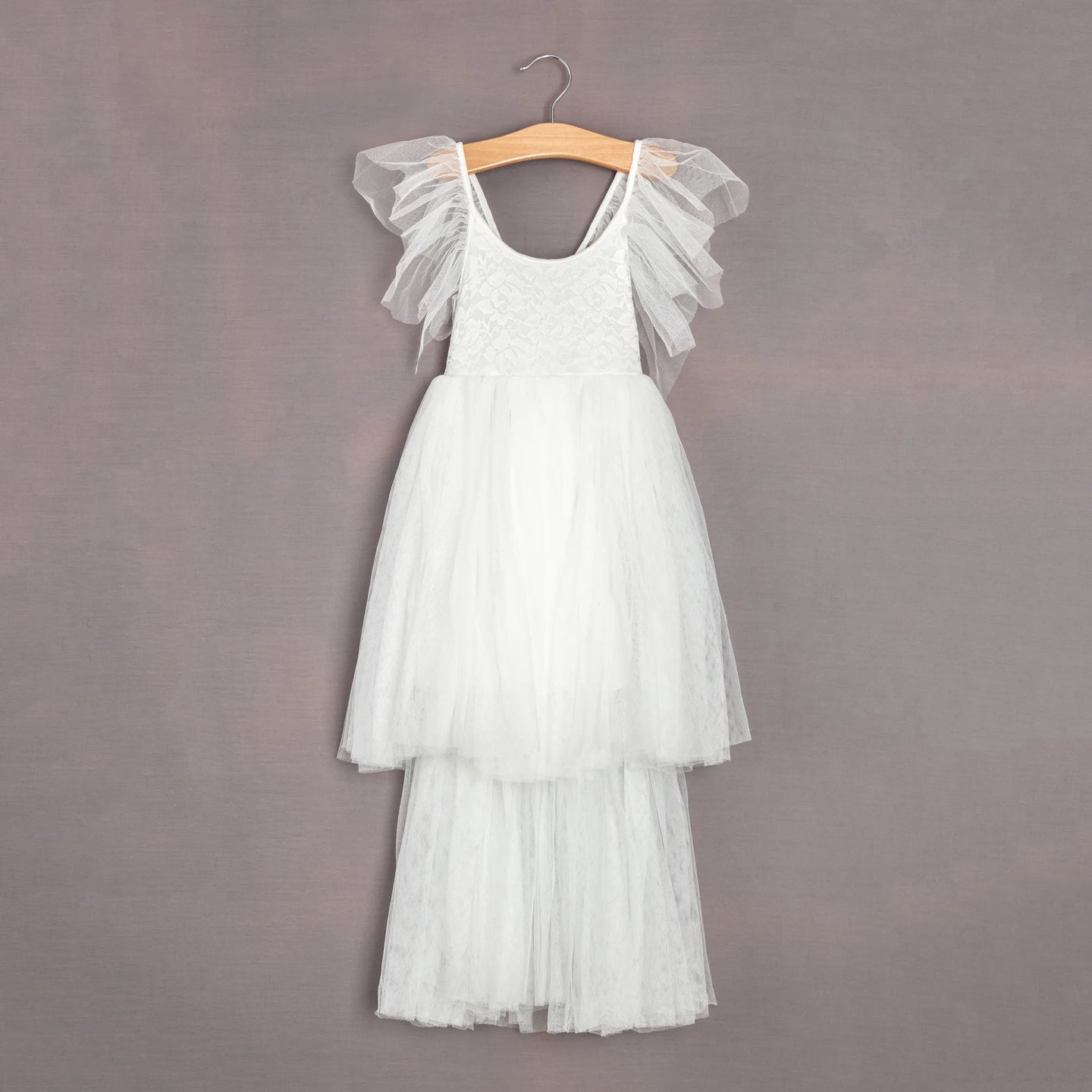White tulle dress on a wooden hanger against a gray background