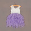 White lace top and purple tulle skirt dress on a hanger against a plain background