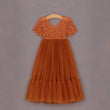 Orange lace dress on a hanger against a gray background