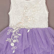 White lace top with floral embellishments and a purple tulle skirt on a neutral background