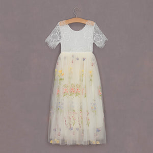 White lace top and floral tulle skirt on a hanger against a gray background