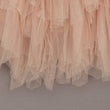Close-up of a layered tulle skirt in a soft apricot color on a neutral background.