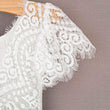 White lace fabric on a wooden hanger against a brown background