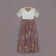 Two-tone dress with lace top and floral skirt on a hanger against a purple background