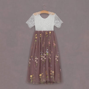 Two-tone dress with lace top and floral skirt on a hanger against a purple background