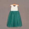 Teal dress with white lace top on a hanger against a brown background