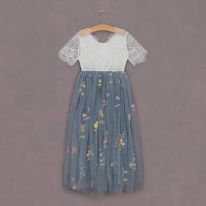 Two-tone dress with lace top and floral skirt on a hanger against a purple background