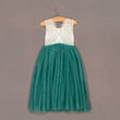 Teal dress with white lace top on a hanger against a brown background