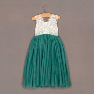 Teal dress with white lace top on a hanger against a brown background