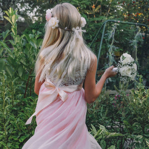 girl with headband and bouquet, standing in a garden.