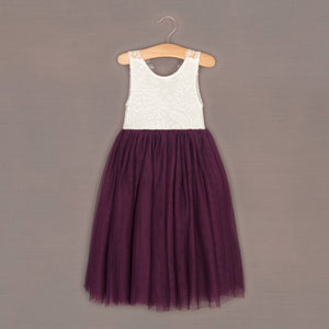 White lace top and purple tulle skirt dress on a hanger against a brown background