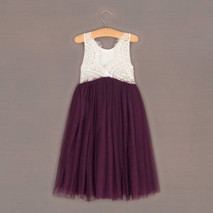 Purple dress with white lace top on a hanger against a gray background