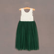 Green dress with white lace top on a hanger against a brown background