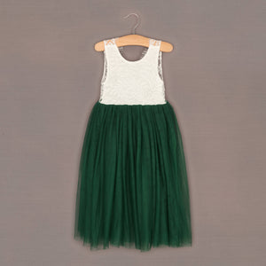 Green dress with white lace top on a hanger against a brown background