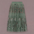 Green pleated skirt with floral pattern on a pink background