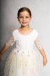 Young girl wearing a white dress with floral embroidery on a gray background