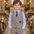 Young boy in a formal suit standing in a decorated church nave.