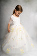 Young girl wearing a white floral dress against a gray background