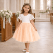 Young girl in a white and peach dress standing in a church.