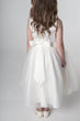 Ivory flower girl dress with a bow on a plain background
