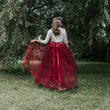 Person wearing a red dress with a white lace top in a park setting