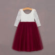 White lace top and red tulle skirt dress on a hanger against a plain background