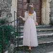 girl in a white lace dress standing on steps outside a stone building.