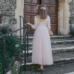 girl in a white lace dress standing on steps outside a stone building.