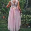 Girl wearing a pink flower girl dress with a white lace top in a garden setting
