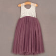 Dress with white lace top and purple skirt on a hanger against a gray background