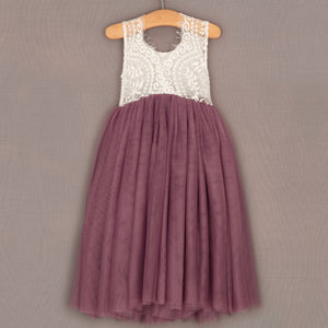Dress with white lace top and purple skirt on a hanger against a gray background