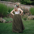 Girl in a green dress with floral headband standing in a garden