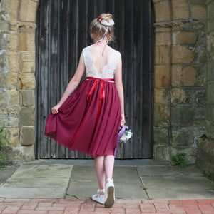 Girl in a red and white dress standing in front of a stone wall.