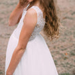 girl wearing a white lace dress against a blurred natural background