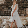 Young girl in a white dress standing against a stone wall.
