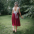 Girl in a red dress with a white lace top walking outdoors on grass.