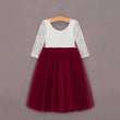White lace top and red tulle skirt dress on a hanger against a gray background