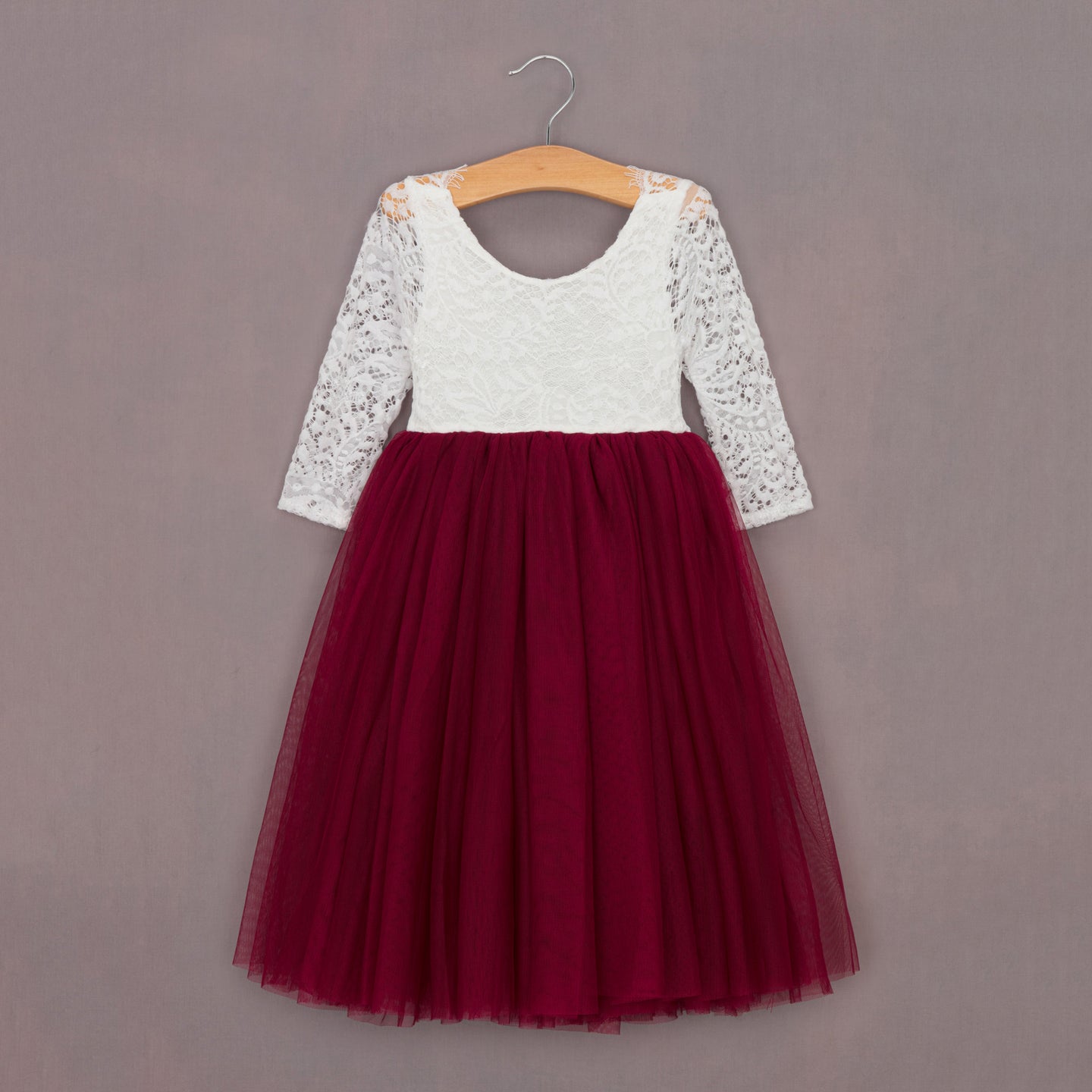 White lace top and red tulle skirt dress on a hanger against a gray background