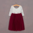White lace top and red tulle skirt dress on a hanger against a gray background