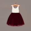 White top with lace details and burgundy tulle skirt on a hanger against a gray background