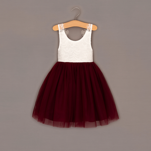 White top with lace details and burgundy tulle skirt on a hanger against a gray background