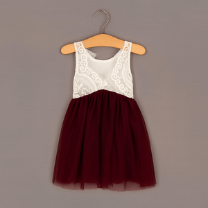 White lace top and burgundy skirt dress on a hanger against a gray background
