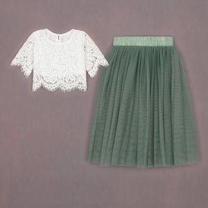 White lace top and green pleated skirt on a brown background
