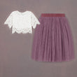 White lace top and purple pleated skirt on a gray background