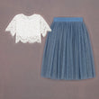 White lace top and blue pleated skirt on a gray background